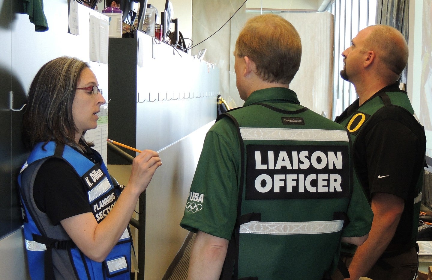 Three people wearing vests, one marked Liaison Officer.