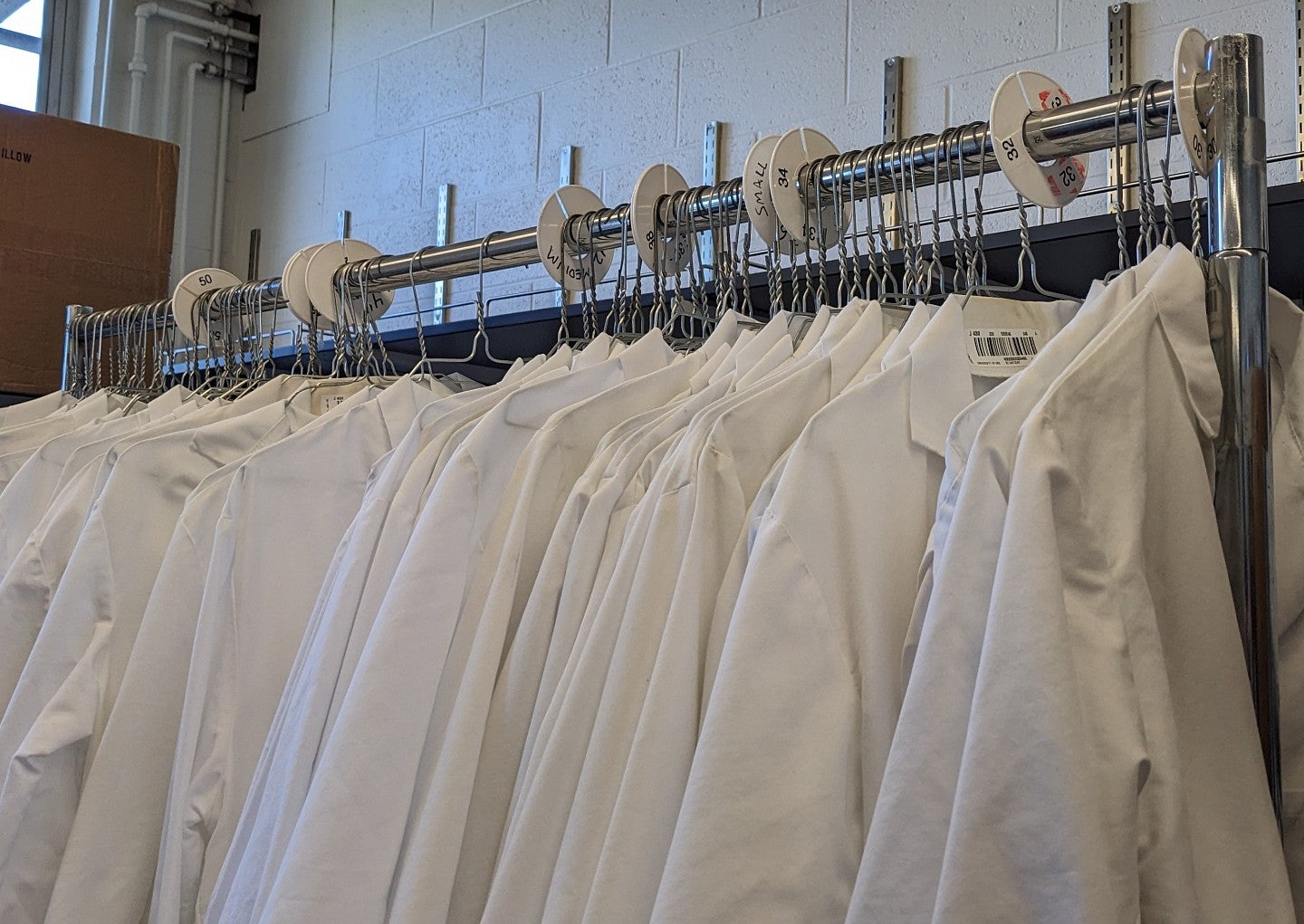 image of white lab coats hanging on a clothing rack