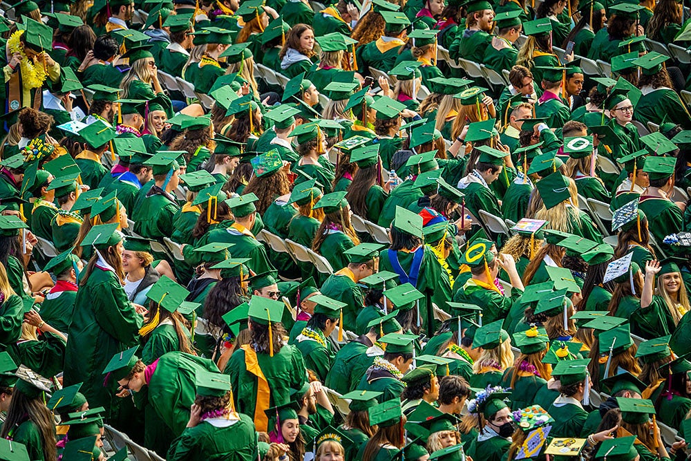 Many students in green caps and gowns at commencement ceremony