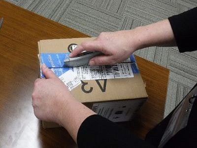 Image of a person using a utility knife to open a box