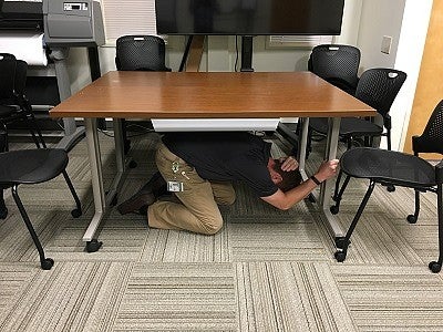 Ducking under a table during earthquake drill