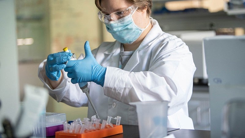 Researcher working in lab wearing ppe including gloves, mask, goggles, and lab coat