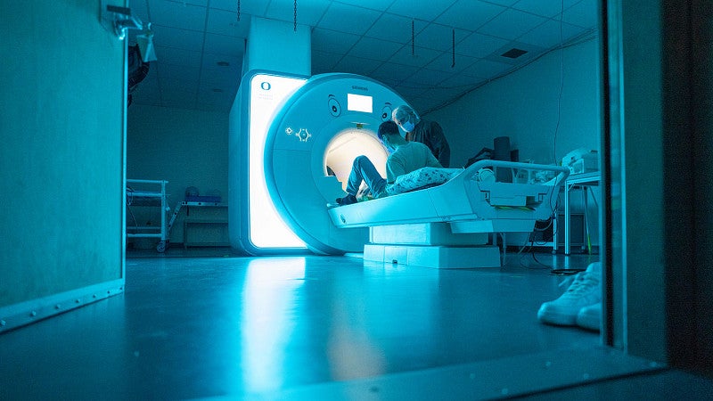 MRI machine with researcher helping a person prepare to enter or leave the machine