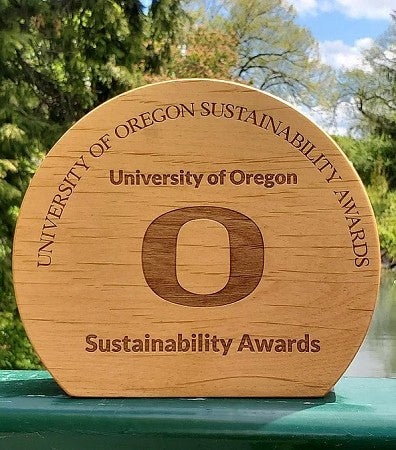University of Oregon susntability award with trees behind