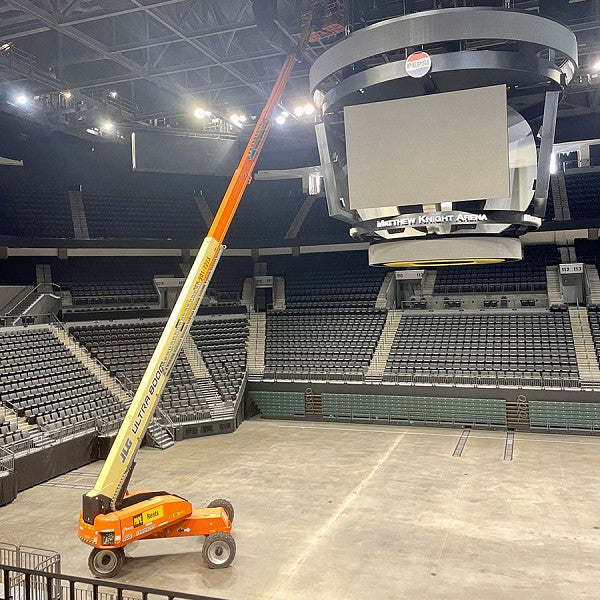 Boom lift inside Matthew Knight Arena stretched above scoreboard